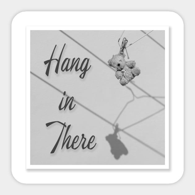 'Hang in There' typography next to a very old tired worn teddy bear hanging out to dry from a coat hanger. Sticker by Earthworx